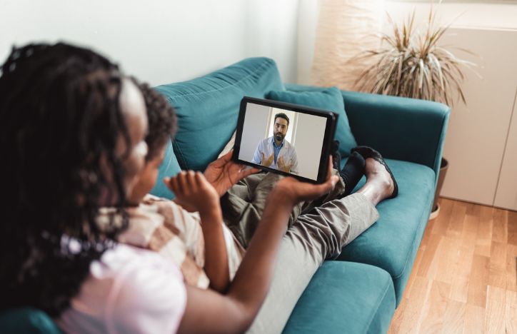 Mother And Child Watching A Video From Their Doctor On A Tablet
