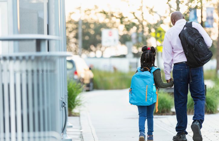 A Father And Daughter Walking Down The Street Together